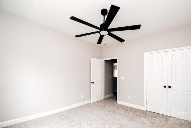 unfurnished bedroom with ceiling fan, light carpet, and a closet