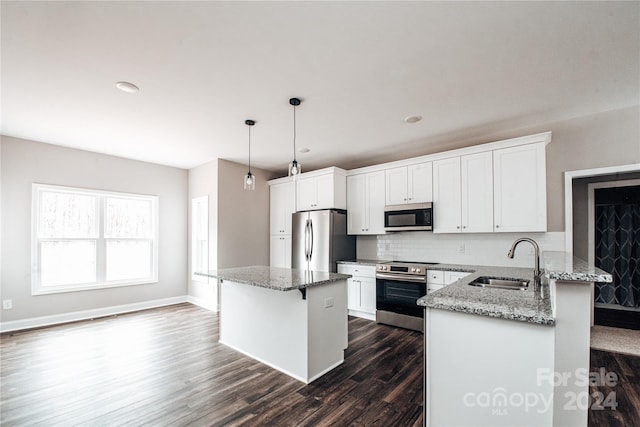 kitchen featuring light stone countertops, sink, dark hardwood / wood-style floors, decorative light fixtures, and appliances with stainless steel finishes