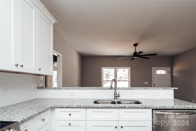 kitchen with stainless steel dishwasher, light stone counters, white cabinetry, and sink