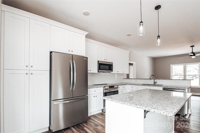 kitchen featuring white cabinets, a kitchen breakfast bar, sink, hanging light fixtures, and stainless steel appliances