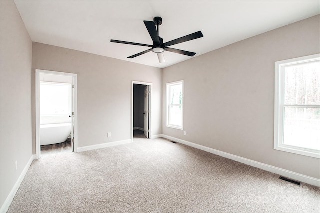 unfurnished bedroom featuring connected bathroom, ceiling fan, and multiple windows