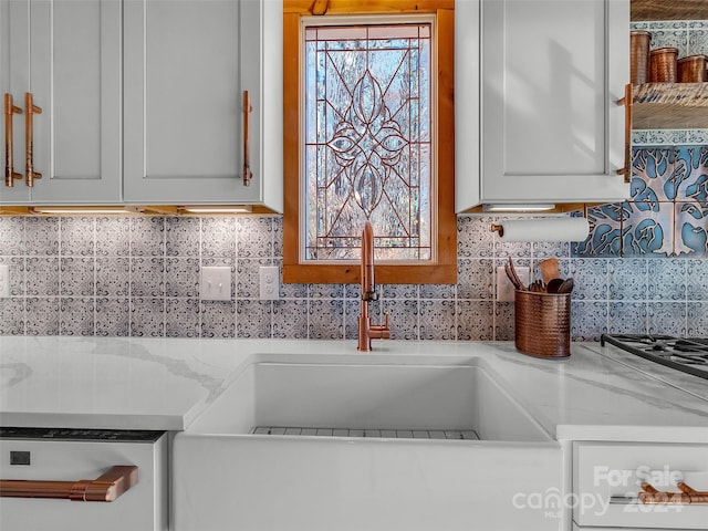 kitchen with white cabinetry, sink, light stone countertops, and backsplash