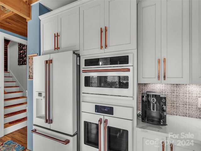 kitchen featuring hardwood / wood-style floors, white appliances, white cabinetry, and backsplash