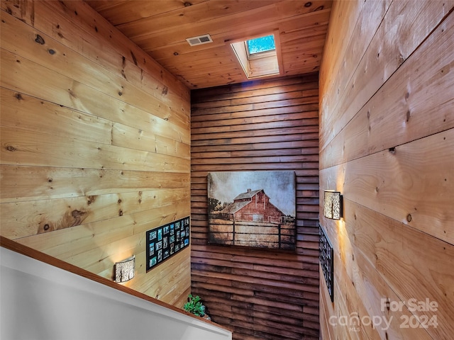 interior space featuring a skylight, wooden walls, and wood ceiling