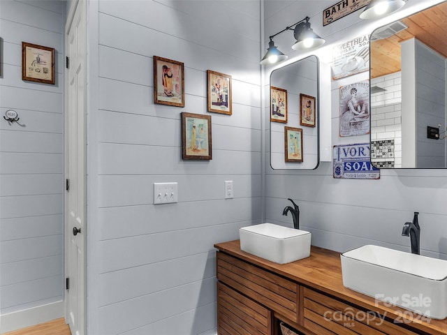 bathroom featuring wood-type flooring, vanity, and wooden walls