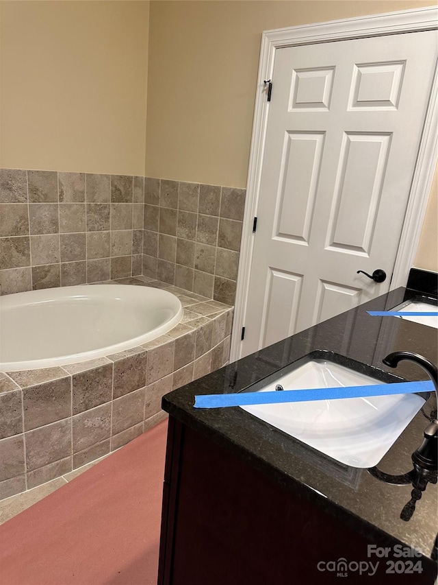 bathroom with vanity and tiled tub