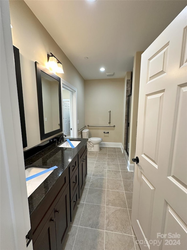 bathroom with tile patterned flooring, vanity, toilet, and a shower with door