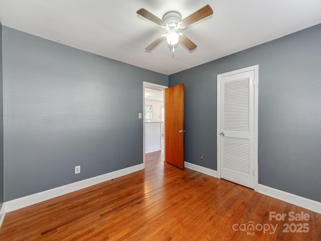 unfurnished bedroom with ceiling fan, wood-type flooring, and a closet