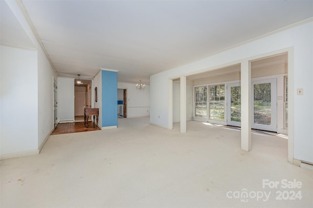 unfurnished living room with carpet flooring, an inviting chandelier, and crown molding