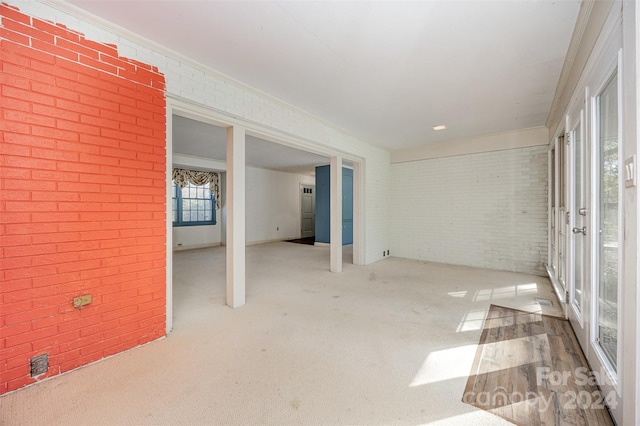 carpeted spare room featuring brick wall