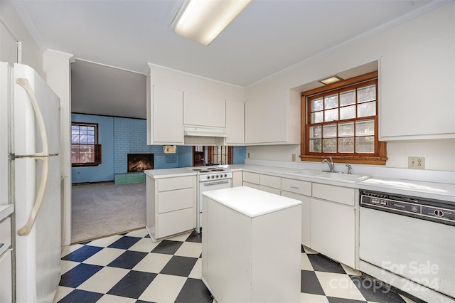 kitchen featuring a center island, white appliances, sink, a fireplace, and white cabinetry