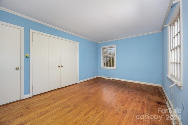 unfurnished bedroom with crown molding, light hardwood / wood-style flooring, and a baseboard radiator