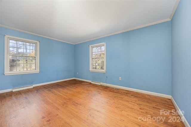 empty room featuring a baseboard radiator, light hardwood / wood-style flooring, and ornamental molding