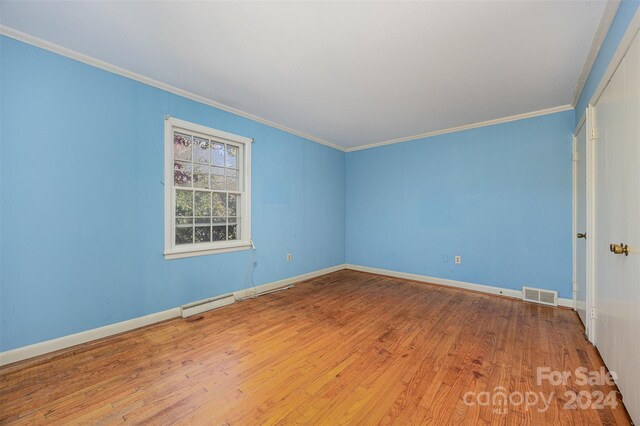 spare room featuring ornamental molding and hardwood / wood-style flooring