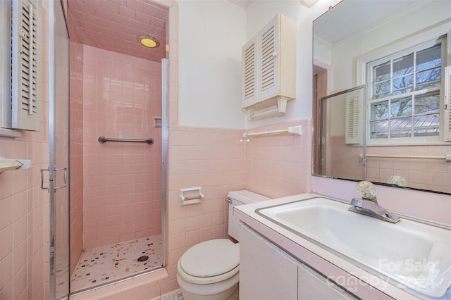 bathroom with an enclosed shower, vanity, toilet, and tile walls