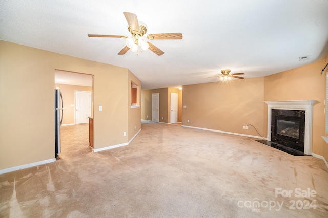 unfurnished living room with ceiling fan, light colored carpet, and a high end fireplace