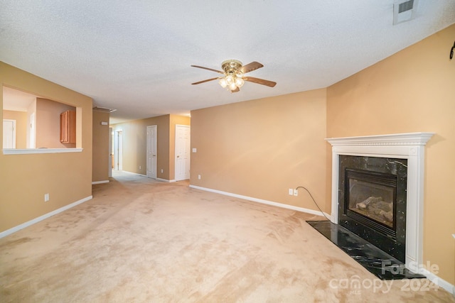 unfurnished living room with ceiling fan, light colored carpet, a premium fireplace, and a textured ceiling