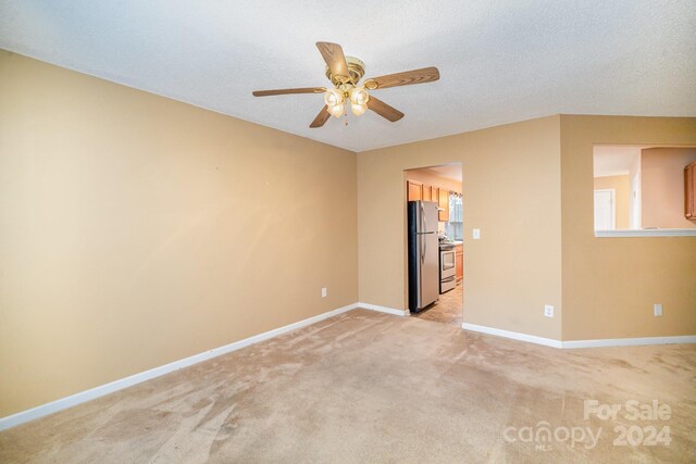 carpeted spare room with a textured ceiling and ceiling fan