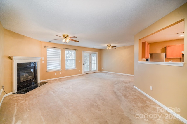 unfurnished living room with a premium fireplace, ceiling fan, light colored carpet, and a textured ceiling