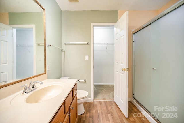 bathroom with walk in shower, toilet, vanity, and hardwood / wood-style flooring