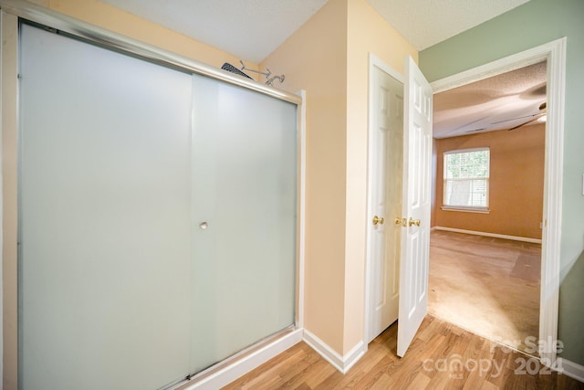 bathroom with hardwood / wood-style floors, ceiling fan, a textured ceiling, and walk in shower