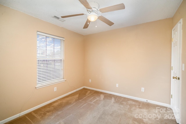 spare room featuring light carpet, a textured ceiling, and ceiling fan