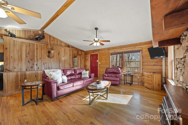 living room featuring light hardwood / wood-style flooring, ceiling fan, and wooden walls