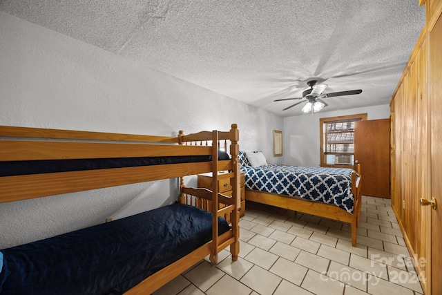 bedroom with ceiling fan, cooling unit, and a textured ceiling