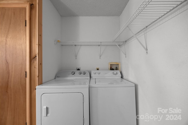 clothes washing area with washer and dryer and a textured ceiling