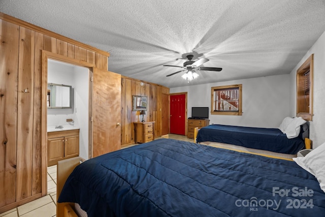 bedroom featuring a textured ceiling, connected bathroom, ceiling fan, and wood walls