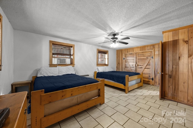 bedroom with ceiling fan, cooling unit, and a textured ceiling