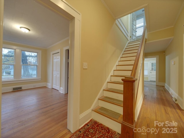 staircase featuring hardwood / wood-style flooring and ornamental molding