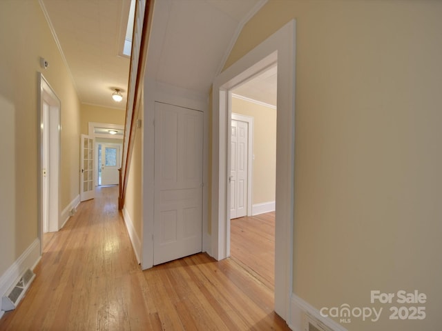 corridor with ornamental molding and light hardwood / wood-style flooring