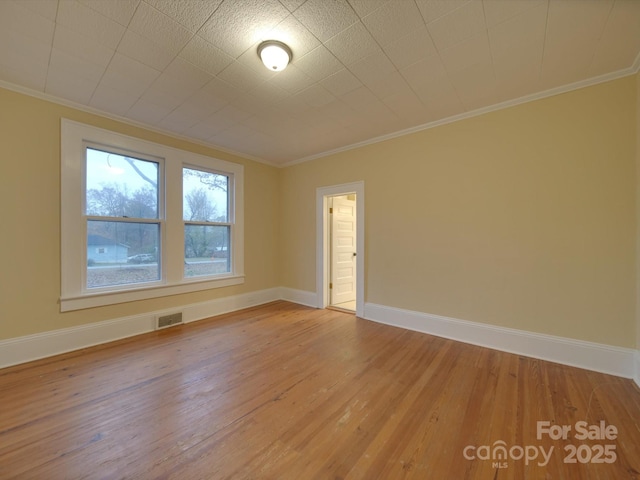 empty room with ornamental molding and hardwood / wood-style floors