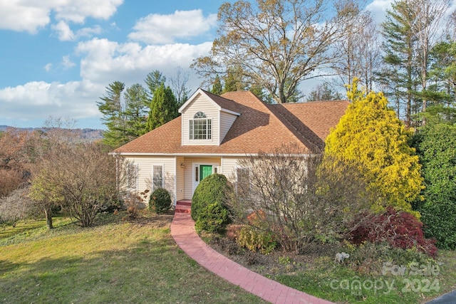 cape cod home featuring a front yard