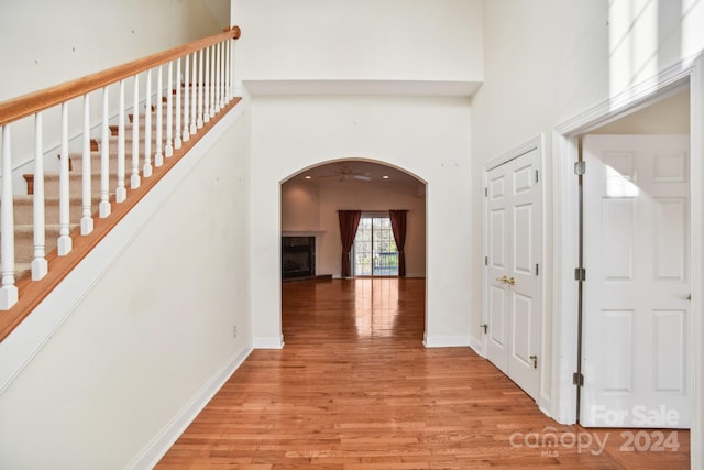 hallway with a towering ceiling and light hardwood / wood-style flooring