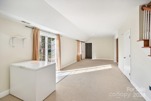 spare room with light carpet and vaulted ceiling