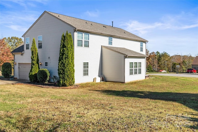 rear view of property featuring a garage and a lawn