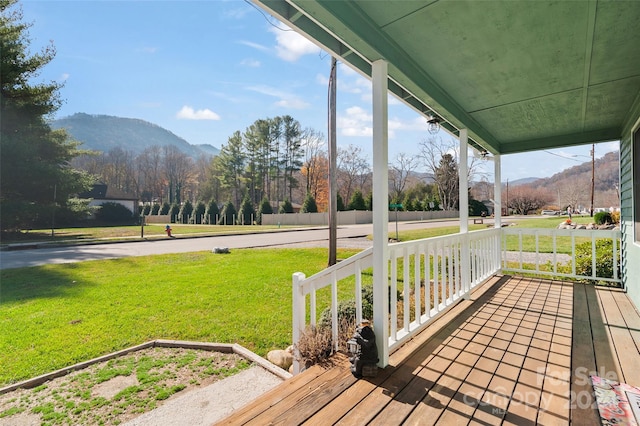 wooden terrace featuring a mountain view, a yard, and a porch