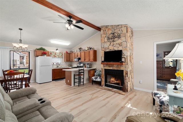 living room featuring ceiling fan with notable chandelier, a stone fireplace, sink, light hardwood / wood-style flooring, and vaulted ceiling with beams