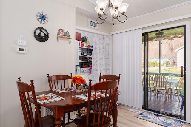 dining area with crown molding, light hardwood / wood-style floors, and an inviting chandelier