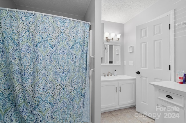 bathroom with a textured ceiling, vanity, tile patterned floors, and a shower with curtain