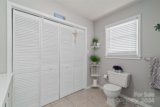 bathroom with tile patterned flooring, a textured ceiling, and toilet