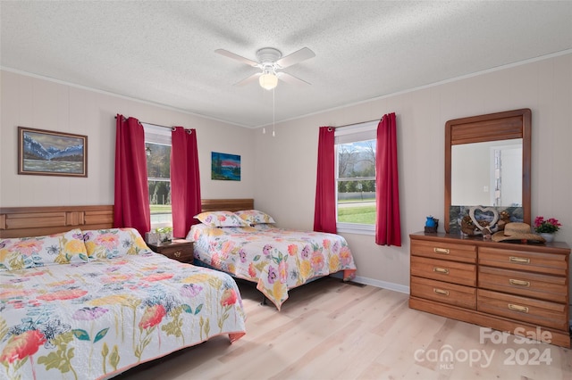 bedroom featuring a textured ceiling, light hardwood / wood-style flooring, ceiling fan, and crown molding