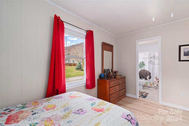 bedroom featuring light hardwood / wood-style floors, ensuite bath, and crown molding