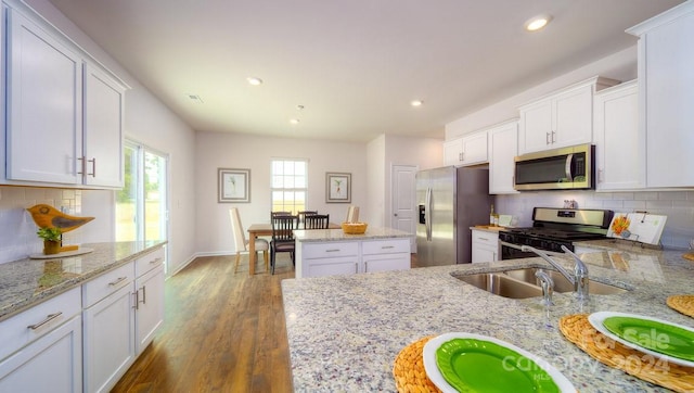 kitchen featuring white cabinetry, light stone counters, dark wood-type flooring, and appliances with stainless steel finishes