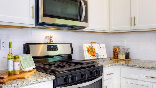 kitchen featuring decorative backsplash, white cabinets, light stone countertops, and appliances with stainless steel finishes