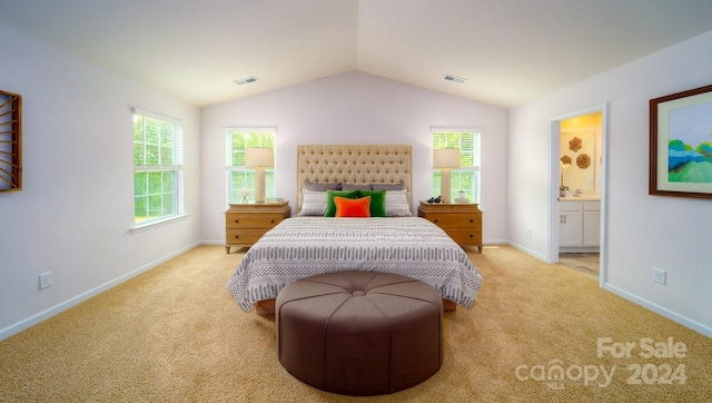 carpeted bedroom with ensuite bath and lofted ceiling