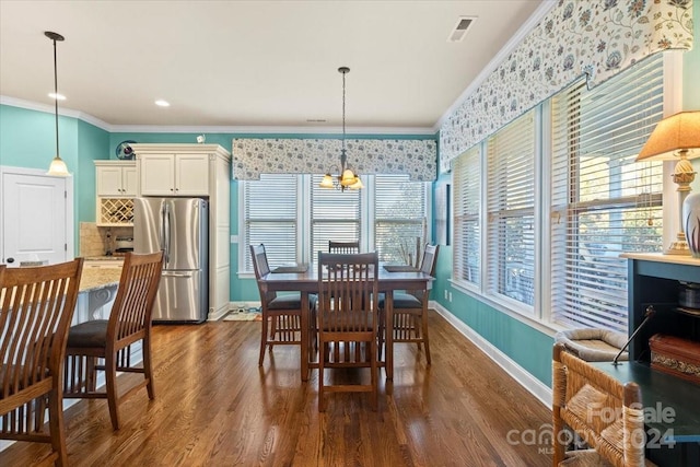 dining area with dark hardwood / wood-style floors, an inviting chandelier, and crown molding