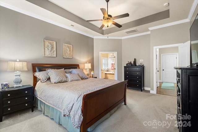 bedroom featuring light carpet, a raised ceiling, ceiling fan, ornamental molding, and connected bathroom